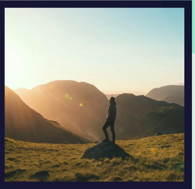 Person standing on a hilltop at sunrise