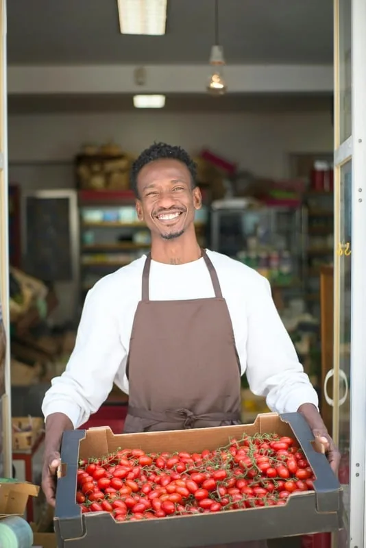 Small business owner holding a crate of tomatoes